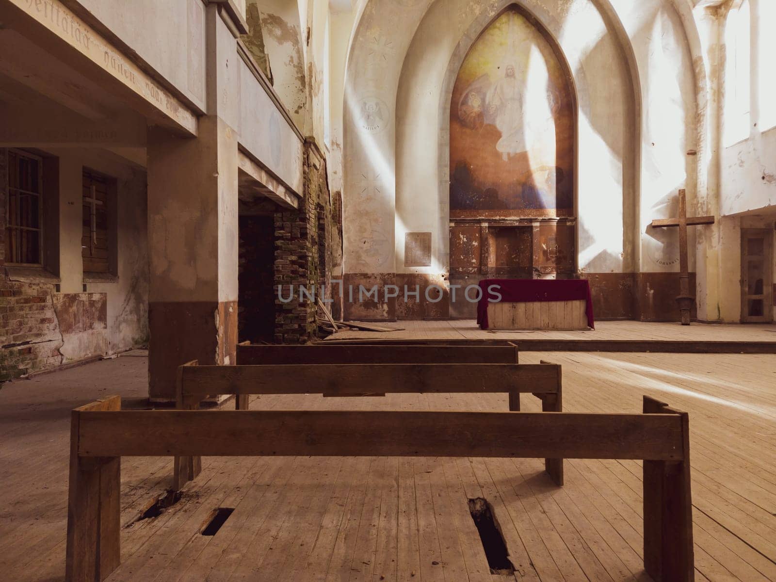 Benches and altar inside an abandoned church. ancient interior of religious building. wooden cross stands in the corner