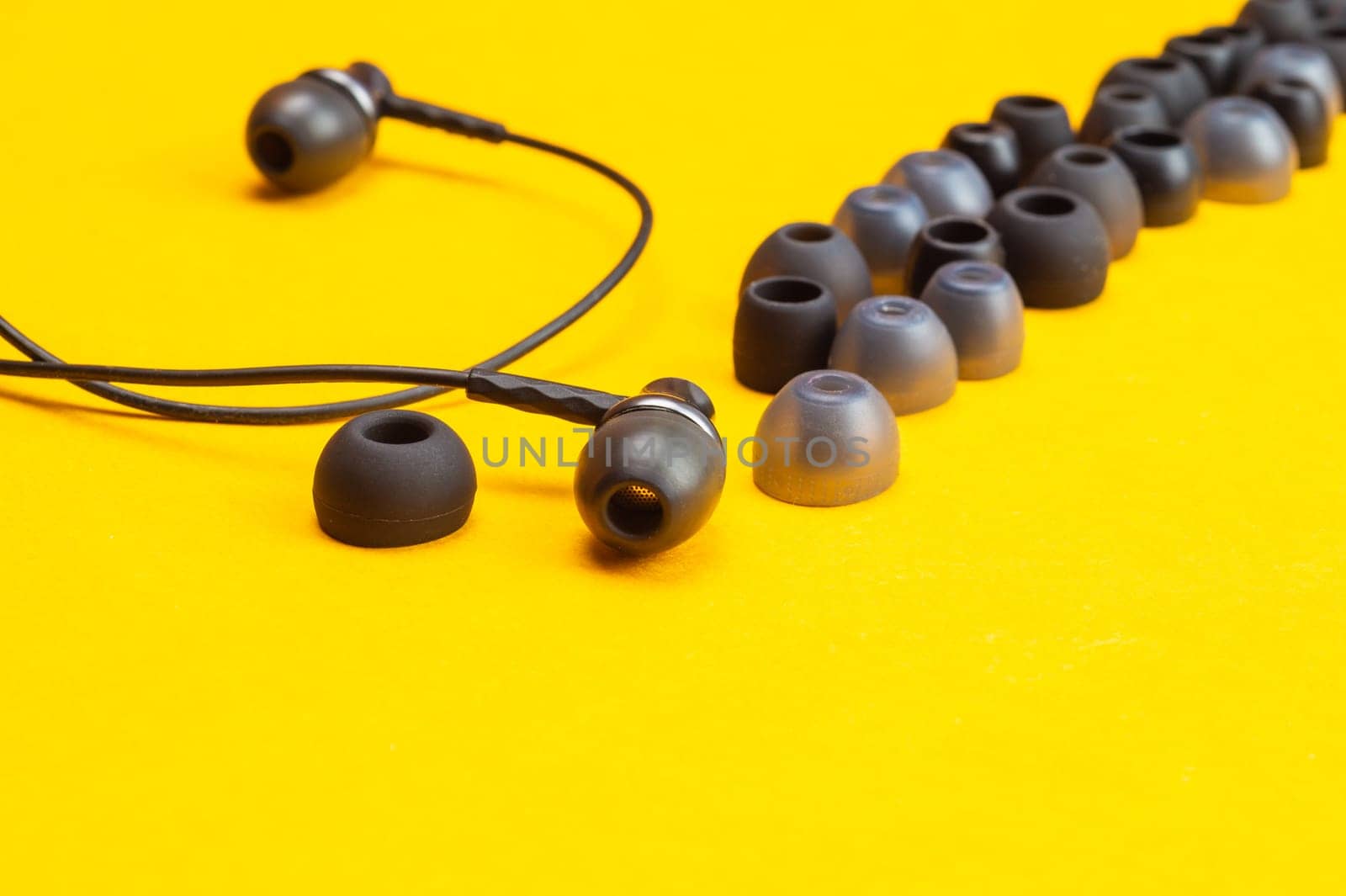 Earphones between of ear cushions on yellow background. in-ear headphones with many embouchures. modern style. audio equipment