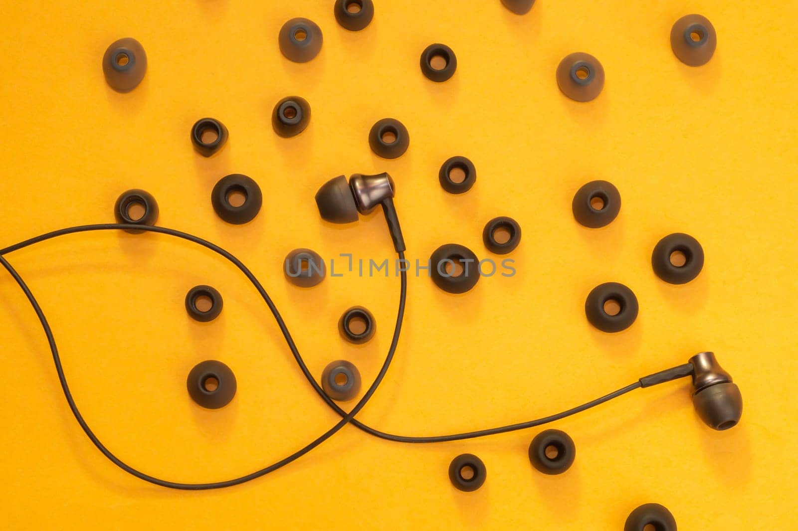 Earphones between of ear cushions on yellow background. in-ear headphones with many embouchures. modern style. audio equipment