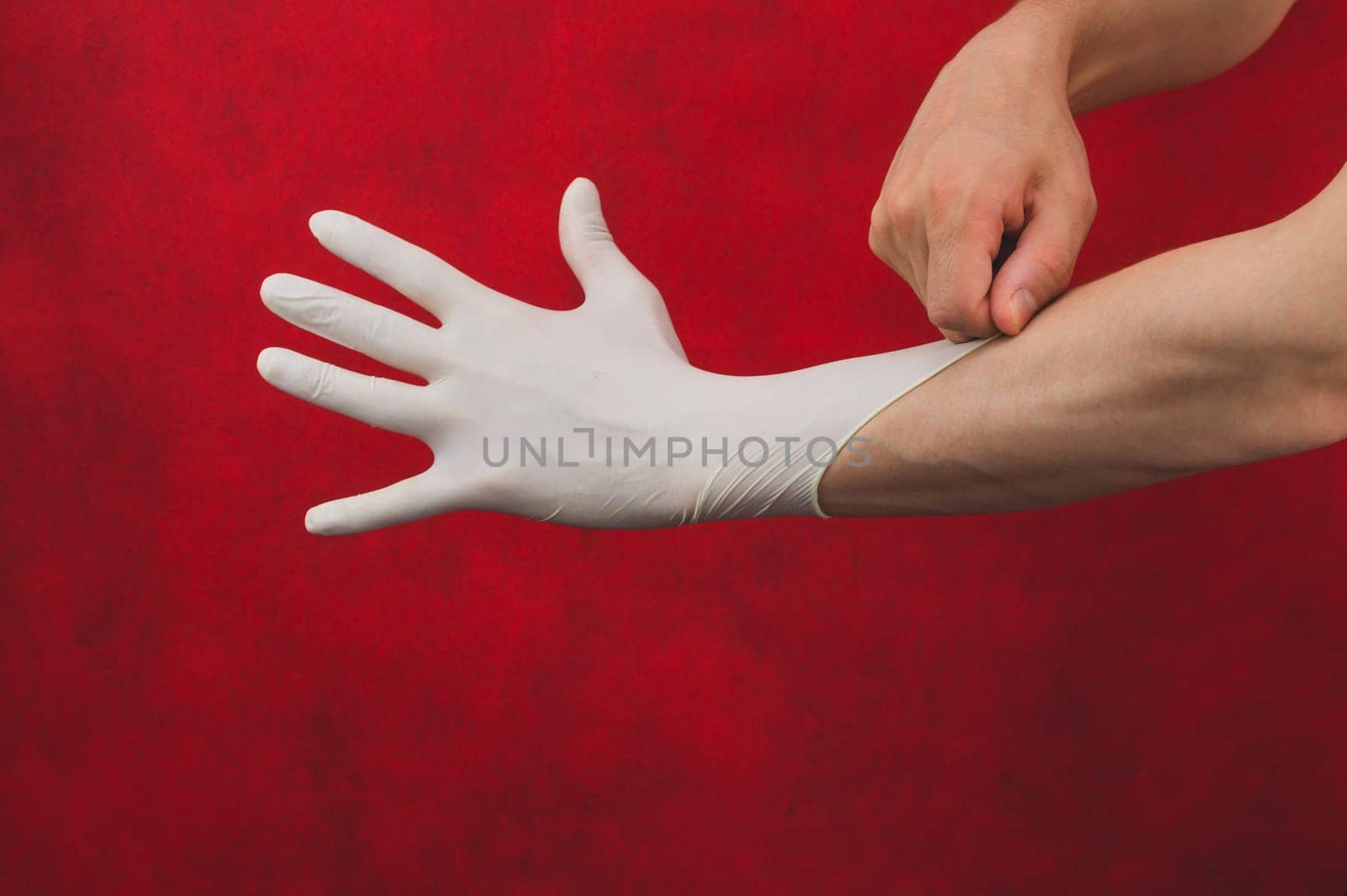Hand in medical glove. person puts on surgical gloves on a red background