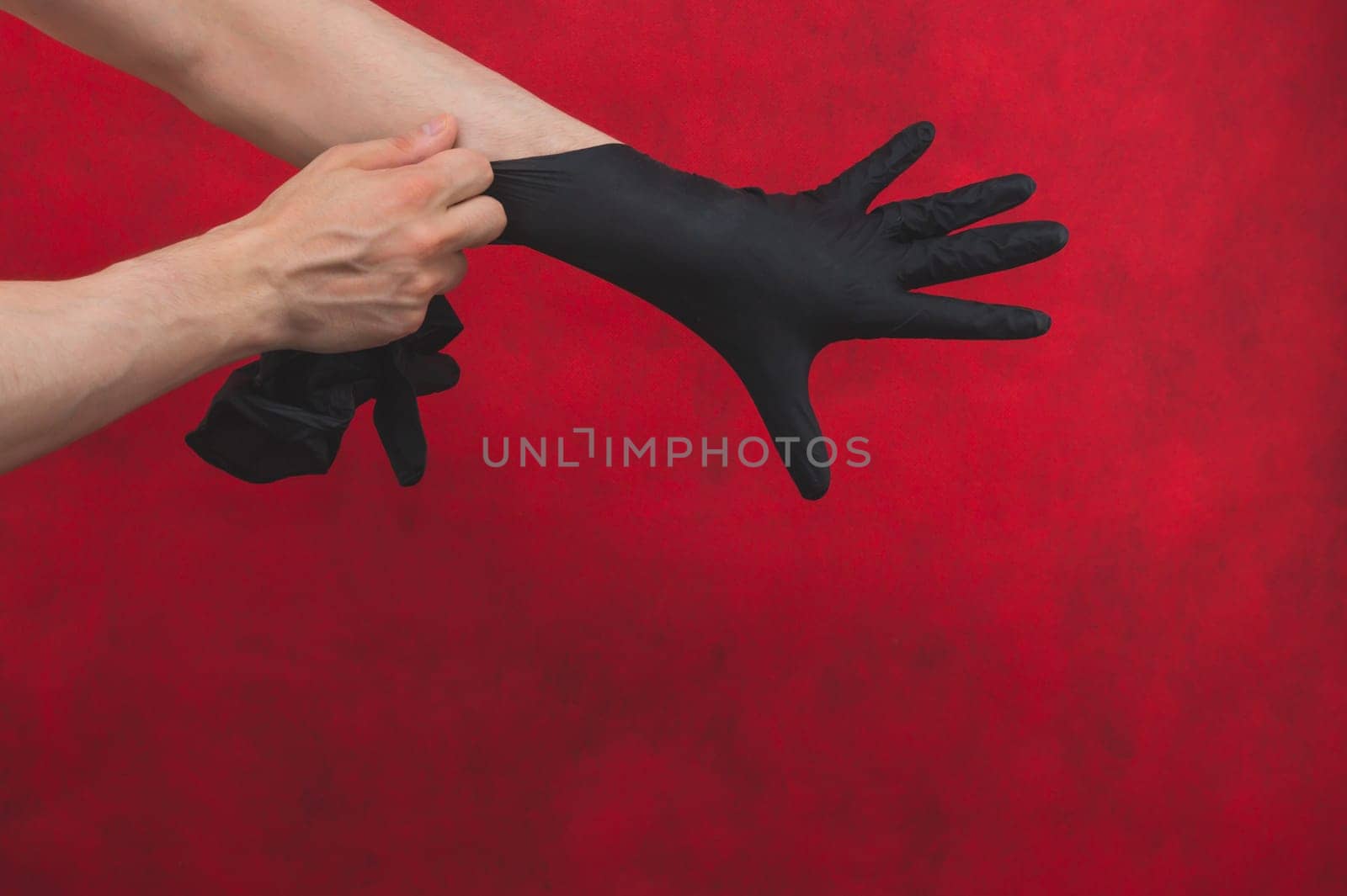 Hands in black medical gloves. person puts on surgical gloves on a red background