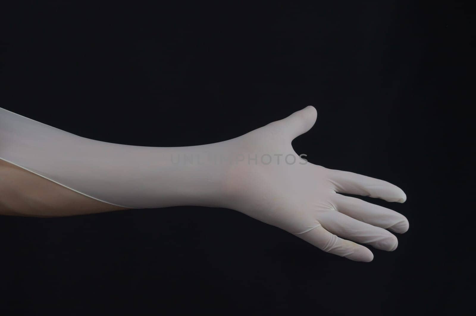 Hand in protective glove on a black background. gesturing hand in white medical glove