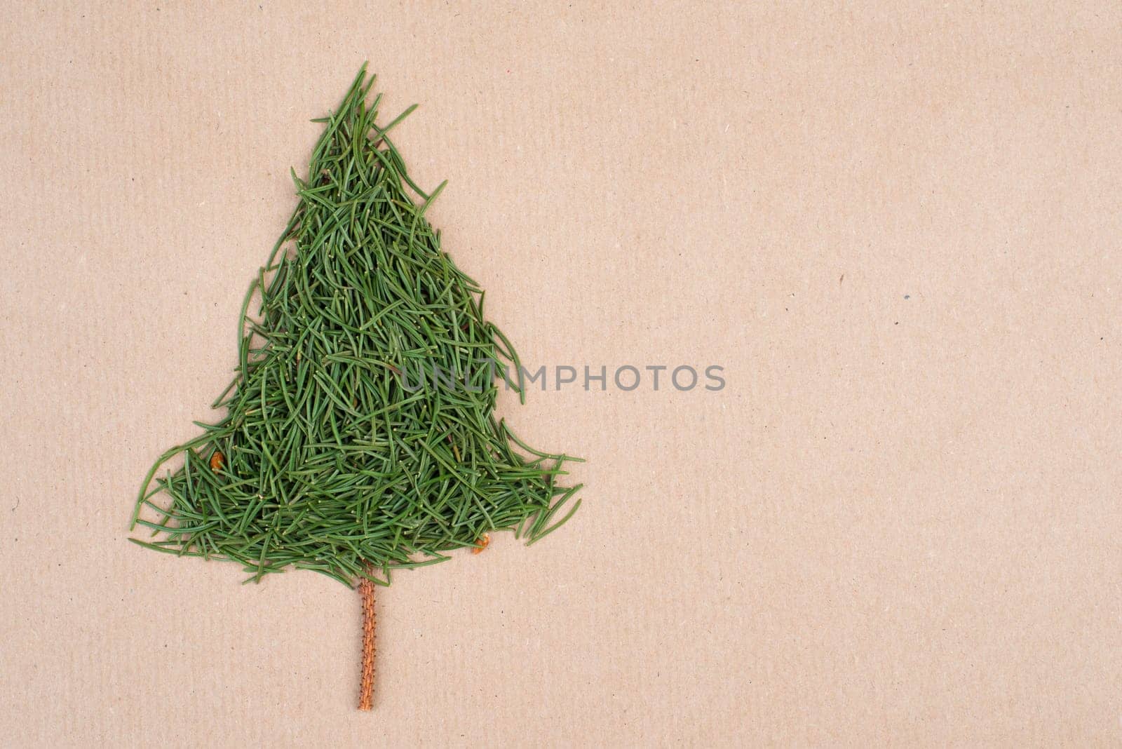 Christmas tree made from fir needles, brown colored paper, copy space, textured background, minimalism