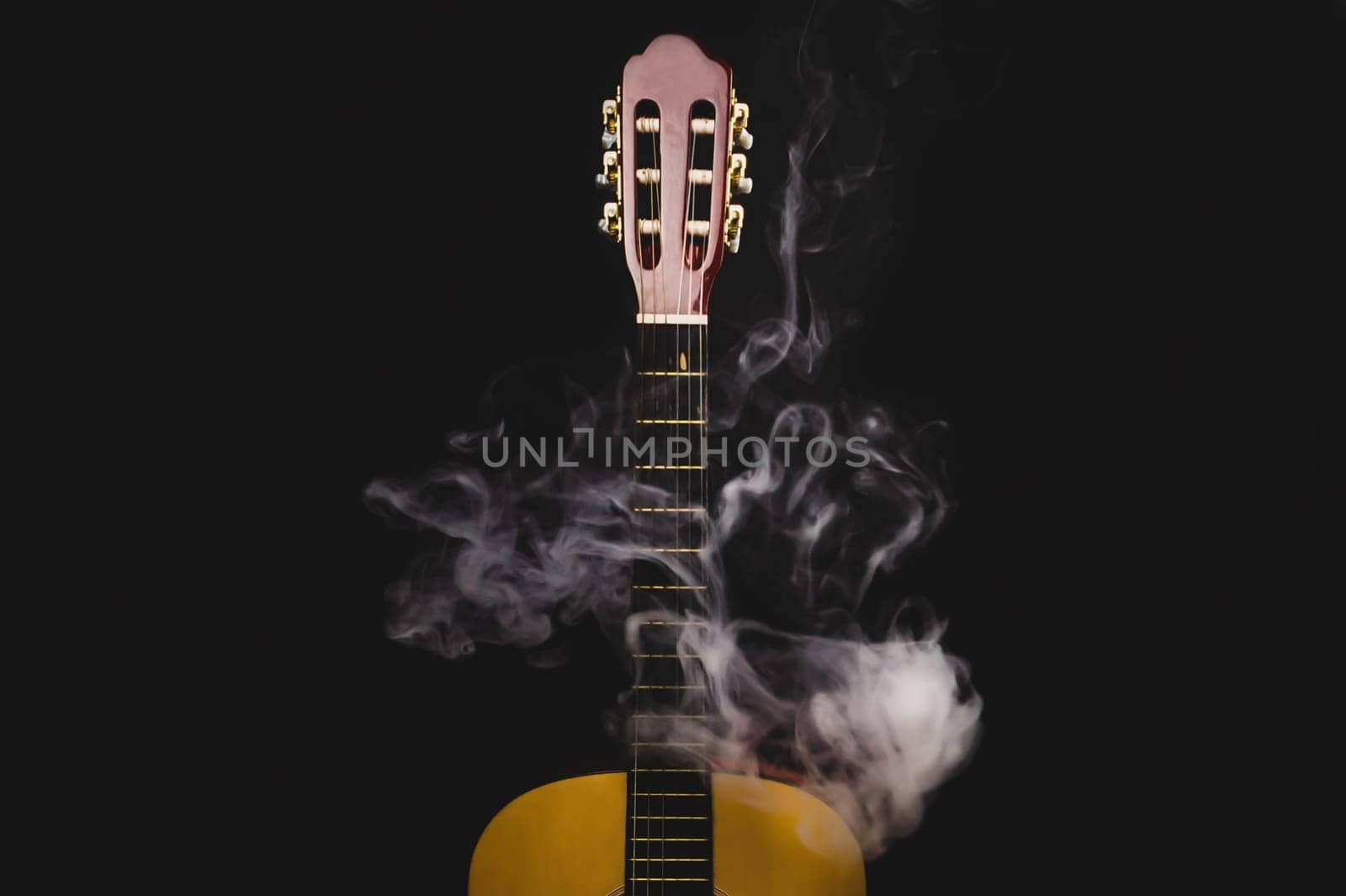 Guitar in smoke on the black background. acoustic musical instrument. strings on the guitar neck