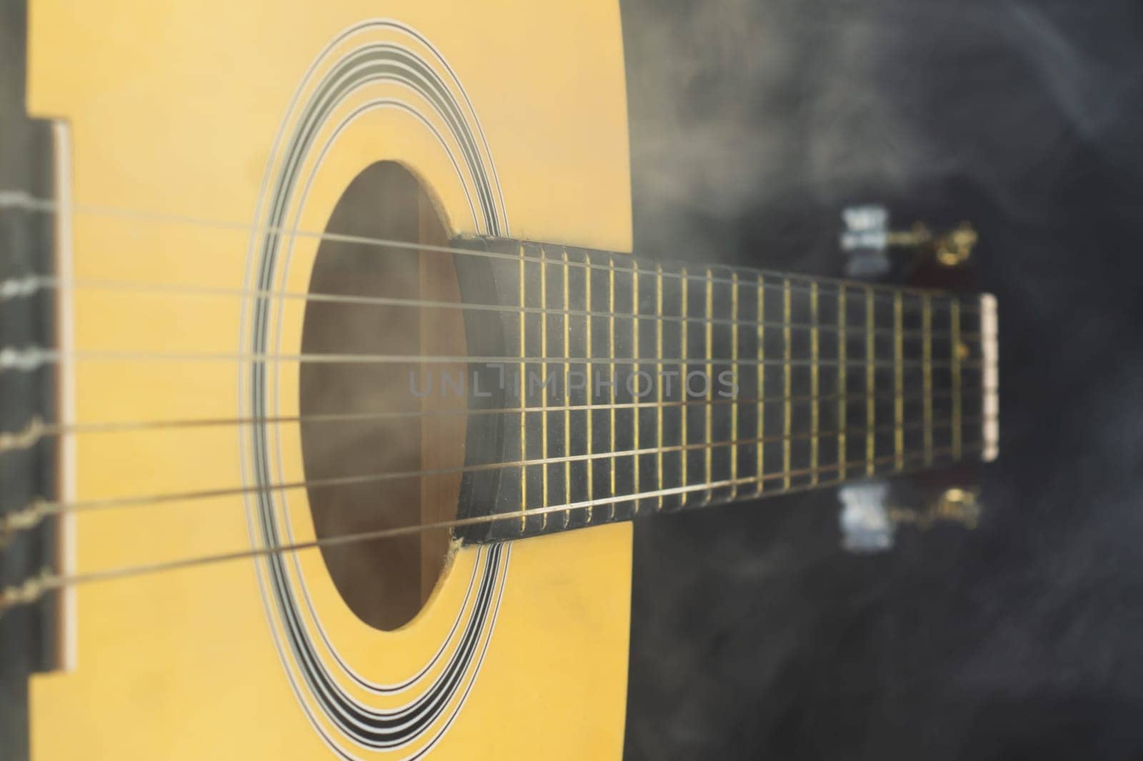 Guitar in smoke close up. acoustic musical instrument. strings on the guitar neck