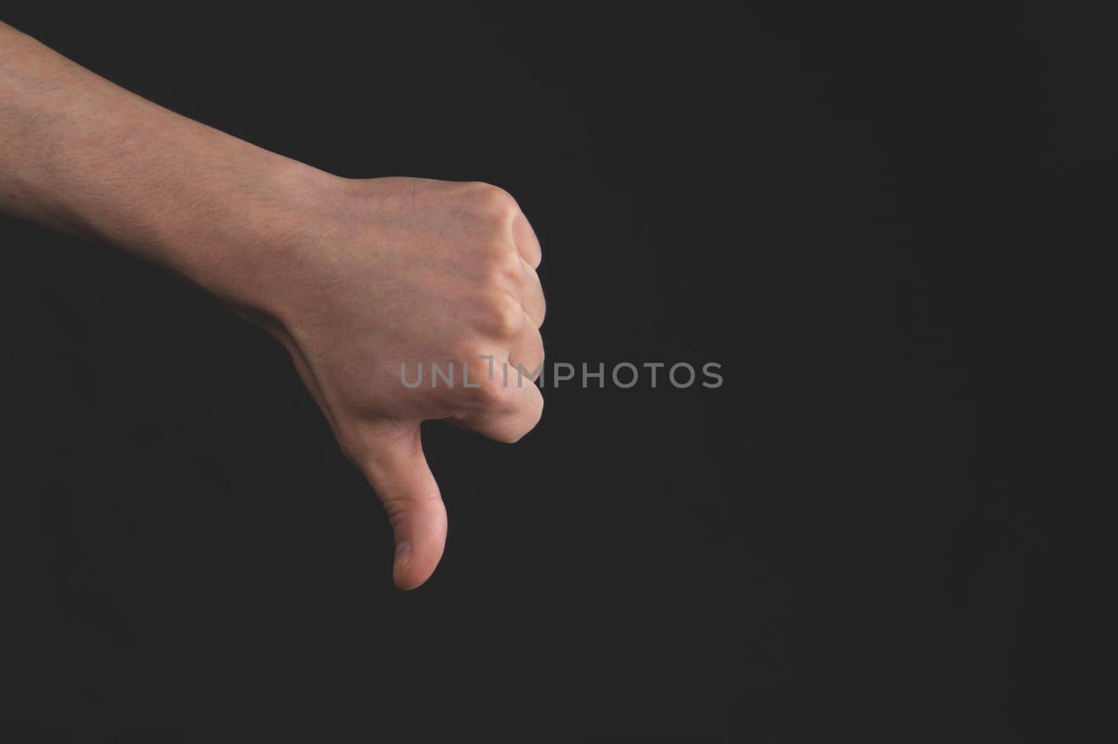 Thumbs down hand on black background. hand lowers big finger