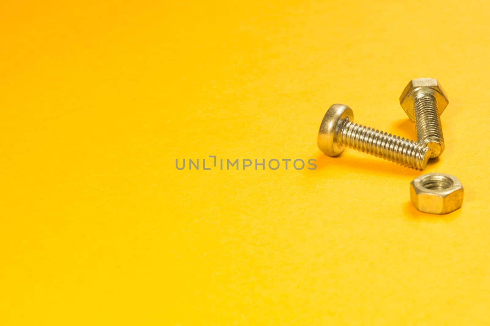 Steel screw on a yellow background. working tools