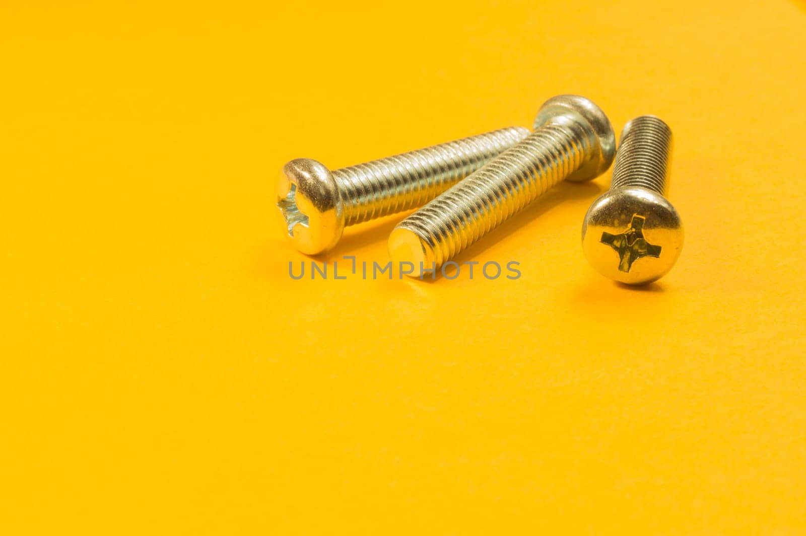 Steel screw on a yellow background. working tools