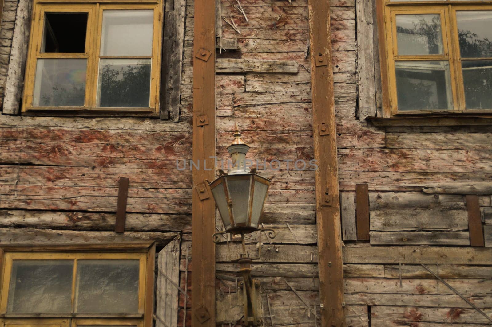Windows of the old wooden house. wooden plank wall with windows and vintage lamp