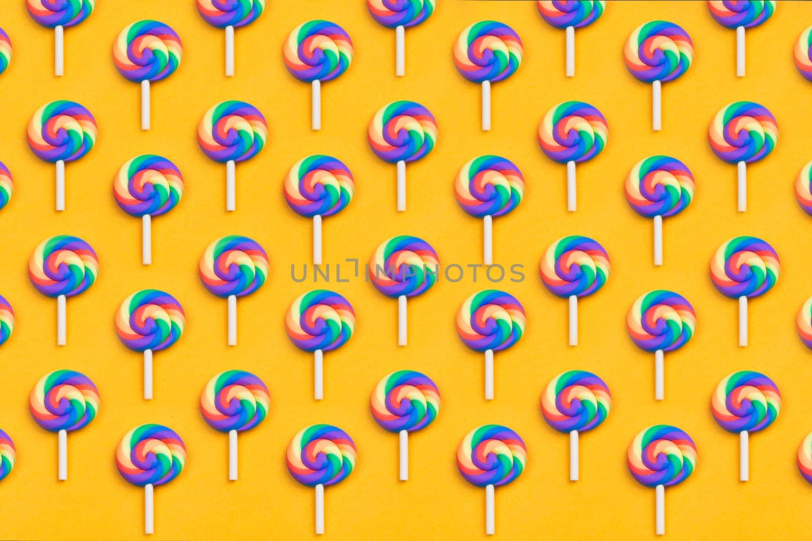 Lollipops are in a row. spiral candy pattern. lots of sweets on a yellow background. festive decoration with candies