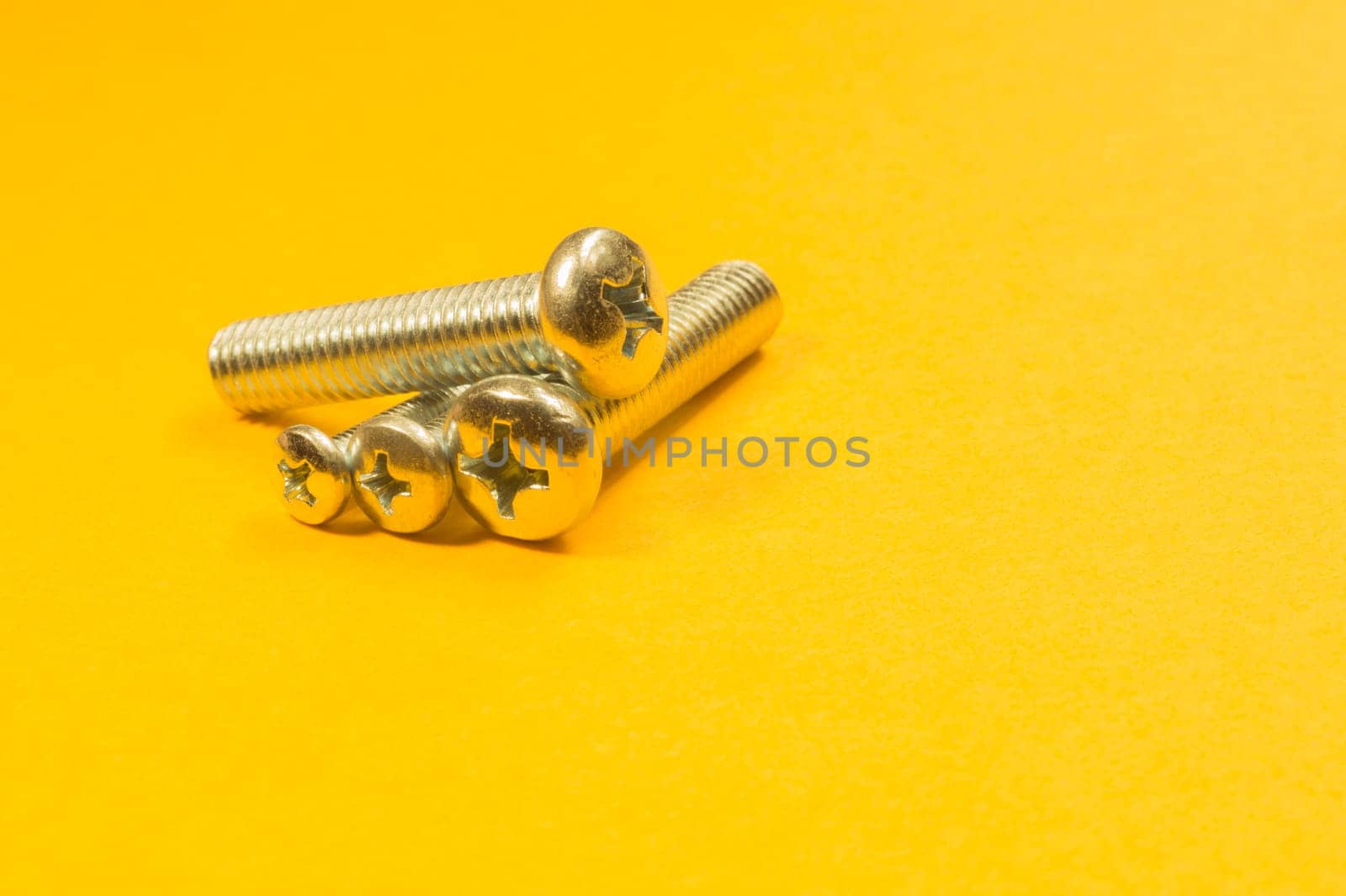 Steel screw on a yellow background. working tools