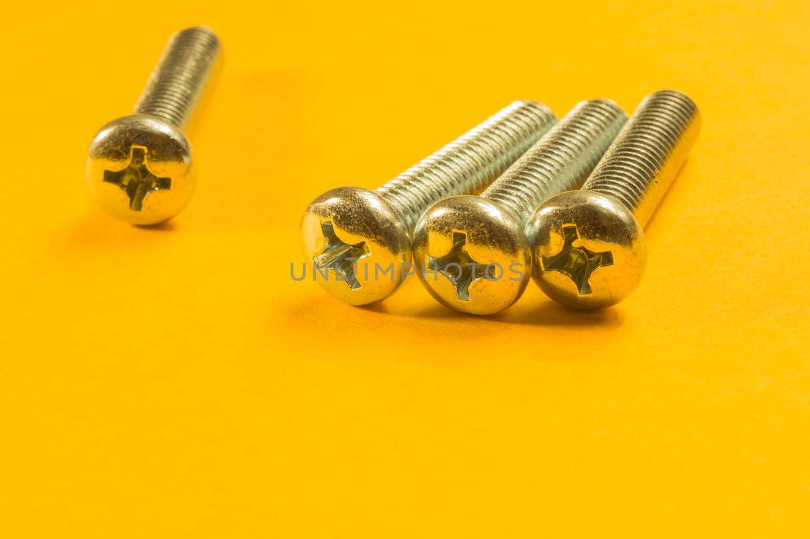 Steel screw on a yellow background. working tools