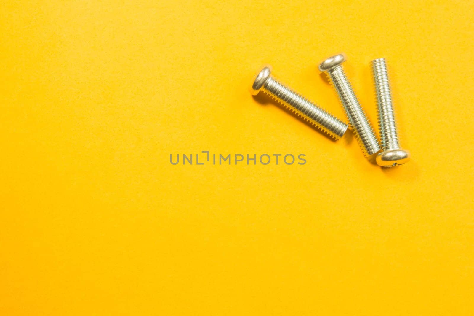 Steel screw on a yellow background. working tools