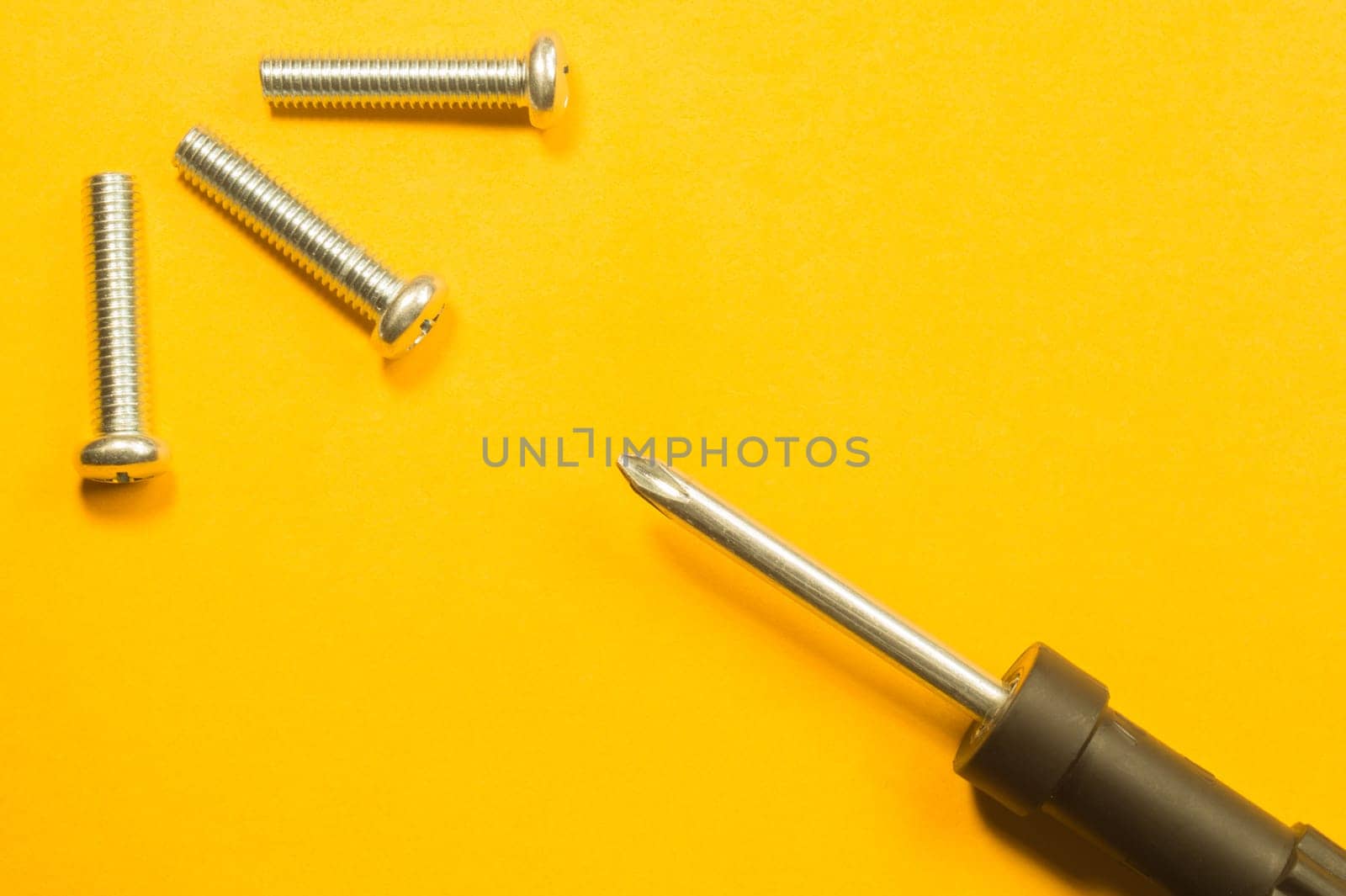 Steel screw on a yellow background. working tools