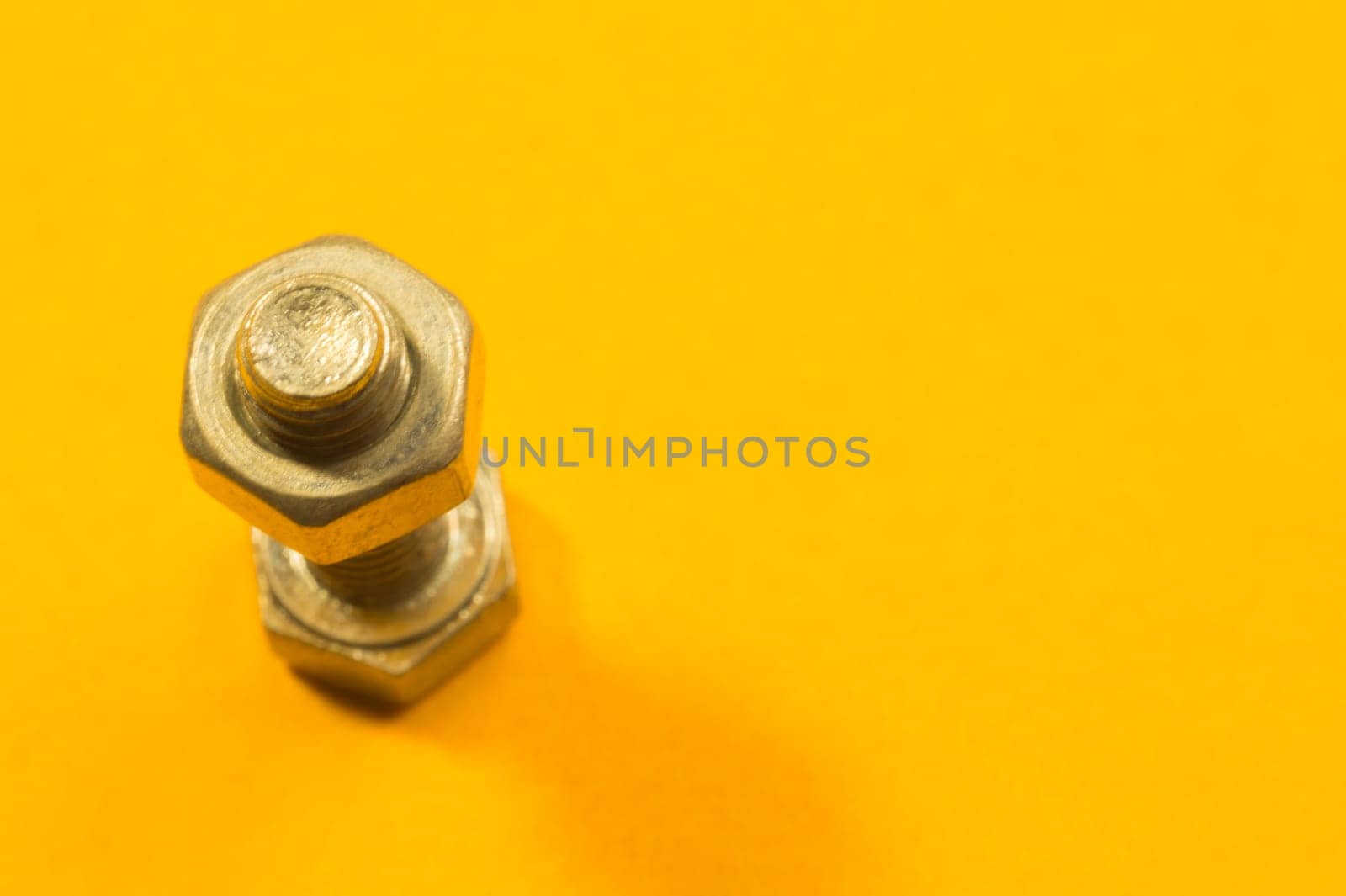 Steel screw on a yellow background. working tools