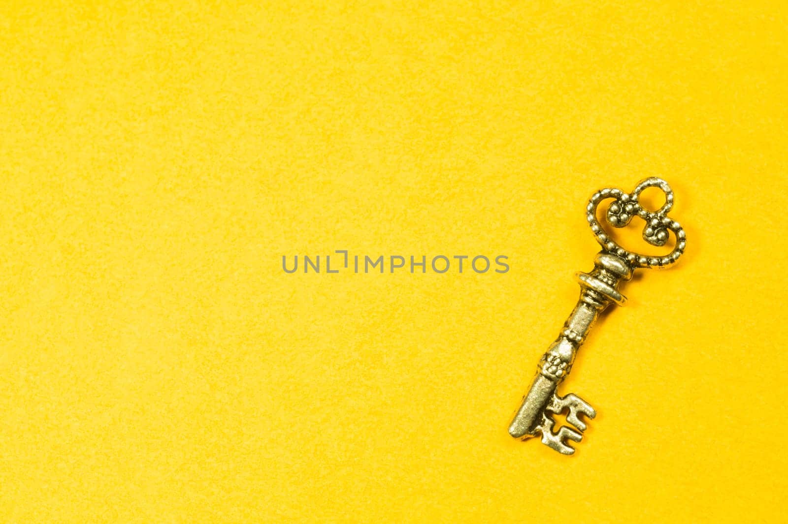 Old key isolated on yellow background. safety and security concept