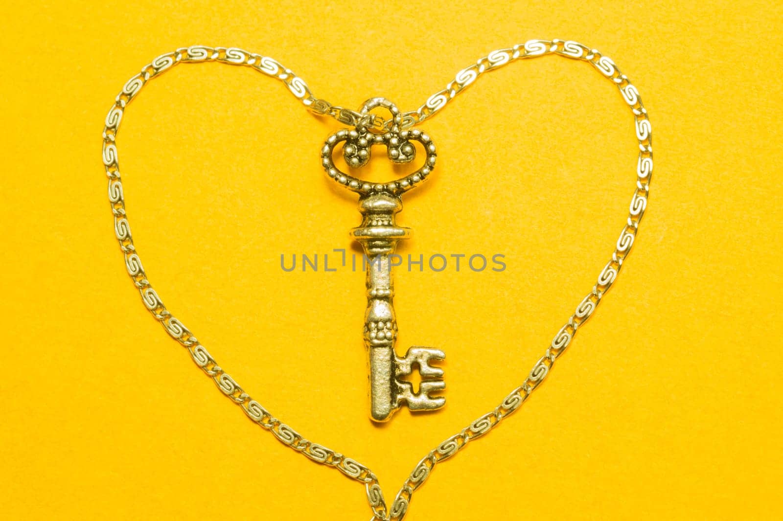 Old key with the chain isolated on yellow background. safety and security concept