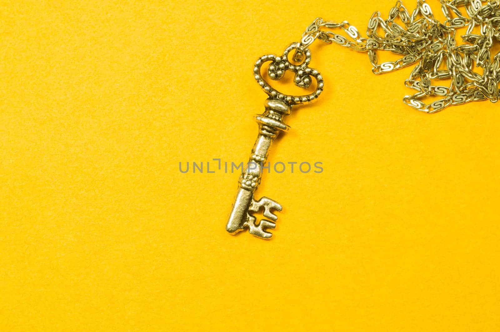 Old key with the chain isolated on yellow background. safety and security concept