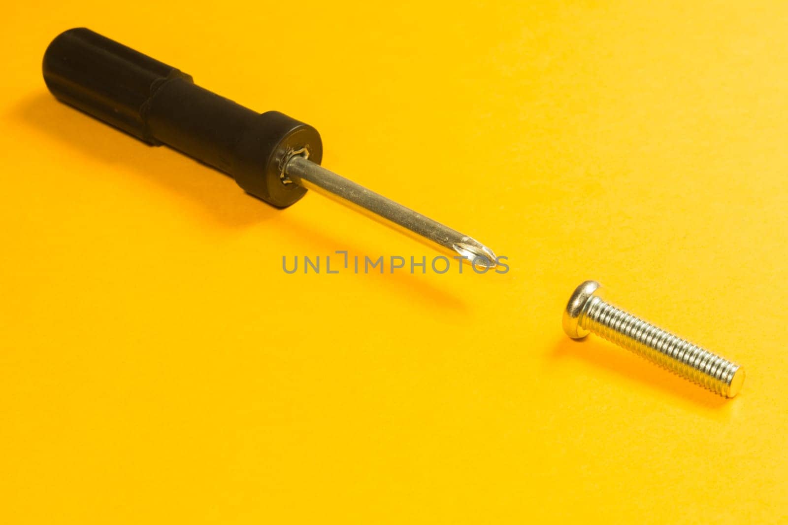 Steel screw on a yellow background. working tools
