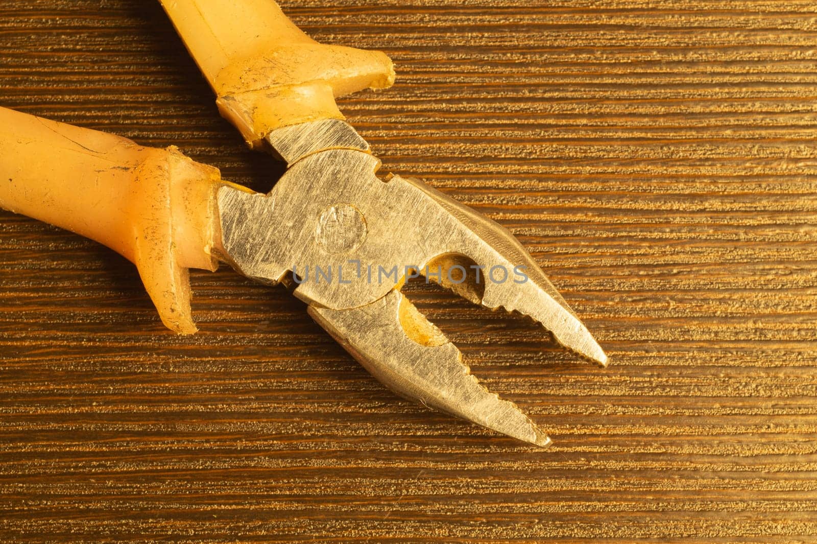 Pliers with orange handles on wooden background. work tool