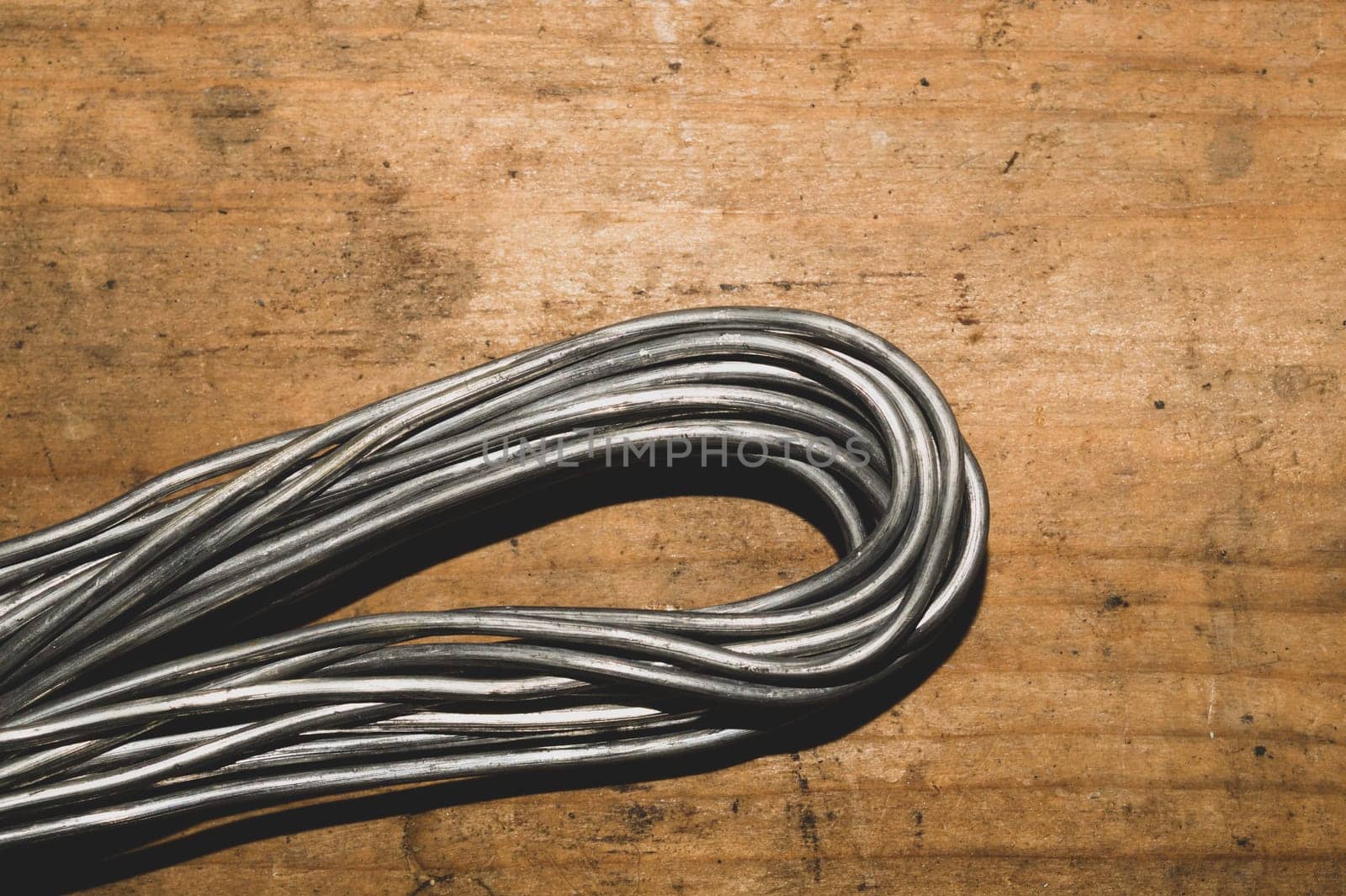 Grey wire on a wood background. wire without braiding lies on the wooden table. work tool