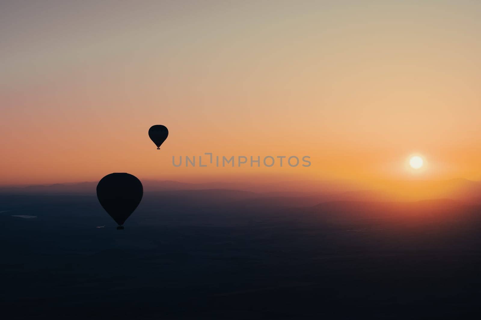 landscape with hot air balloons black silhouette rising up to the sky at sunrise with beautiful high mountain panorama in the background
