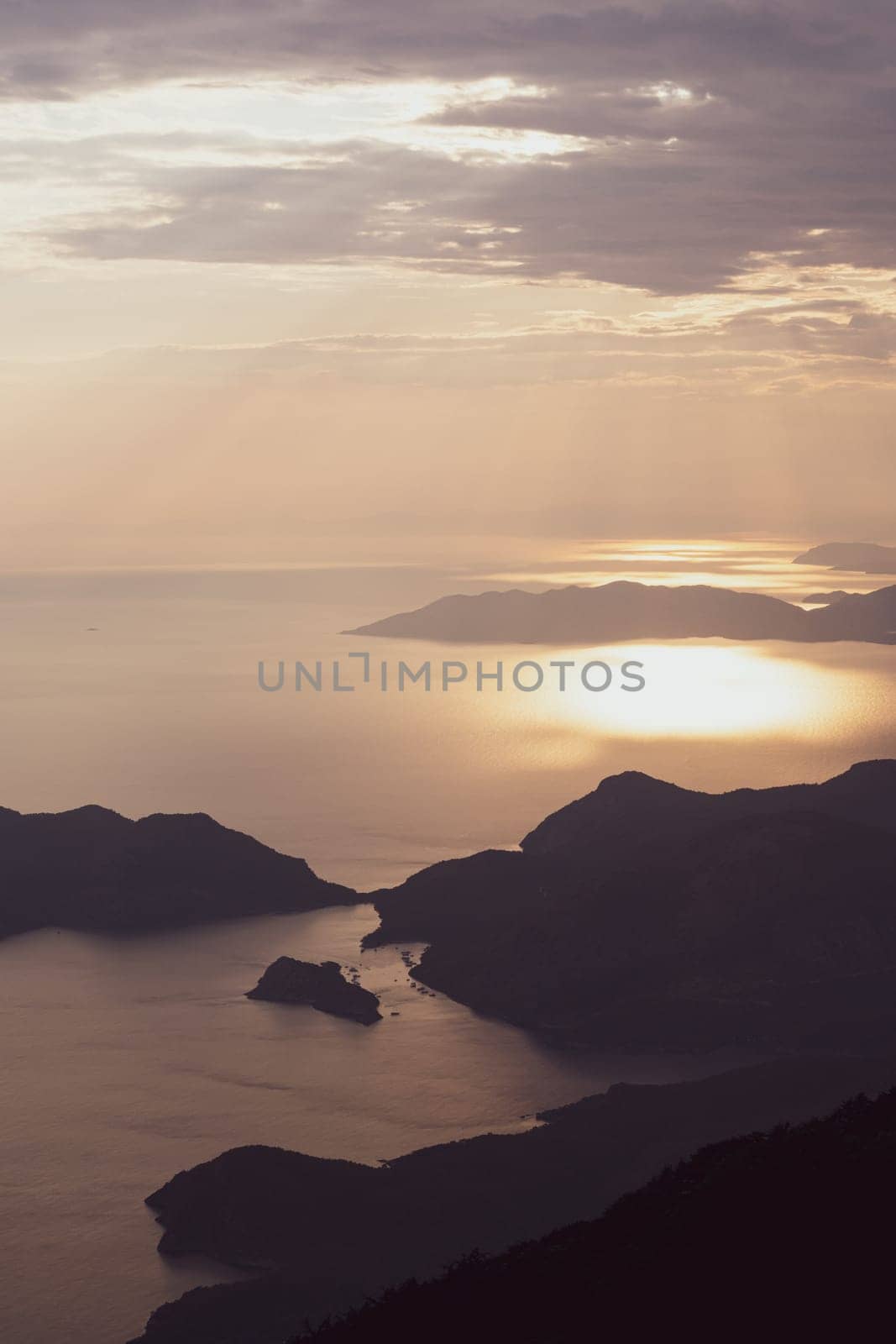 beautiful aerial panorama from the Babadag peak of high mountains rising up over the Mediterranean sea at sunset near Oludeniz Blue Lagoon coast in Turkey during summer