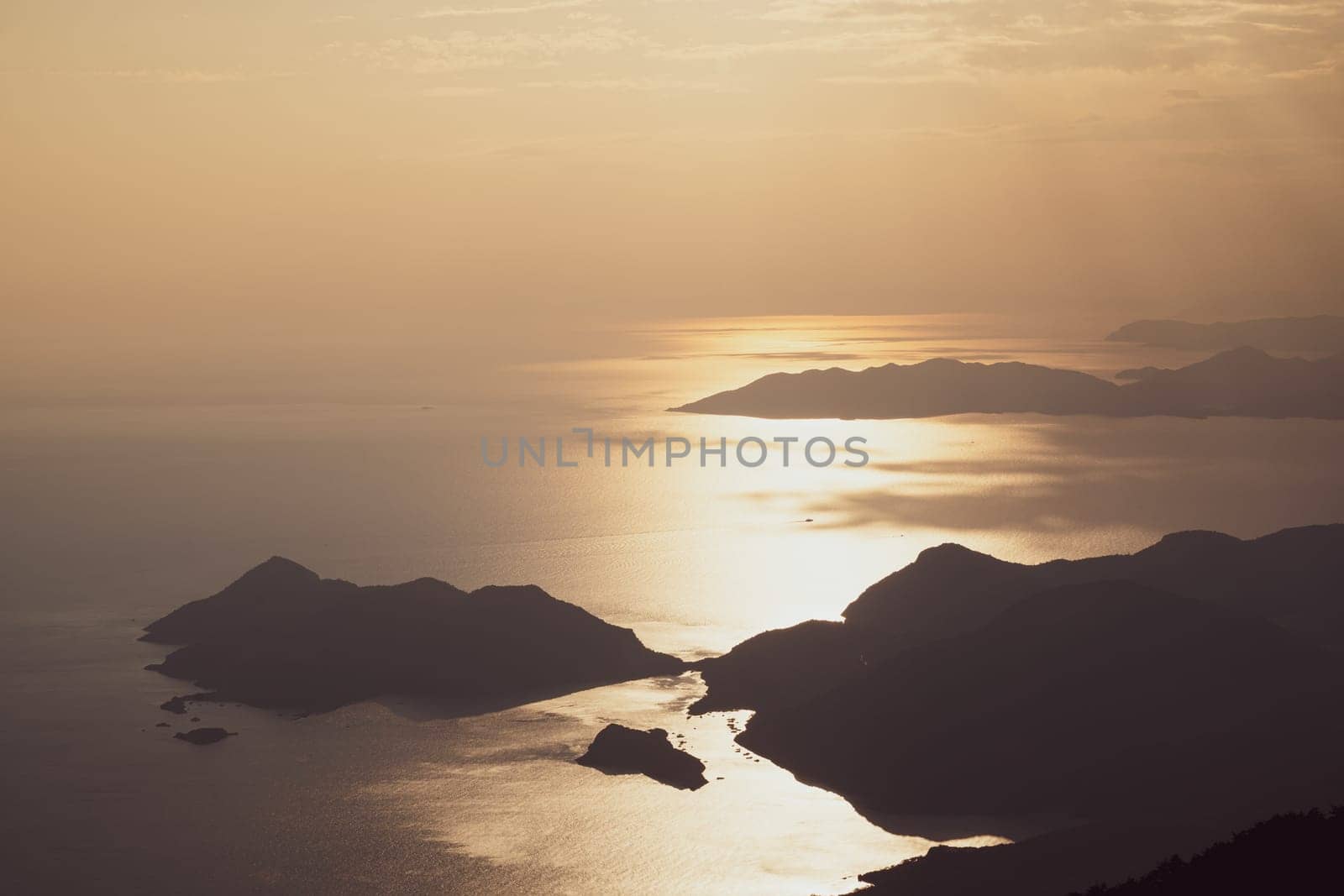 beautiful aerial panorama from the Babadag peak of high mountains rising up over the Mediterranean sea at sunset near Oludeniz Blue Lagoon coast in Turkey during summer