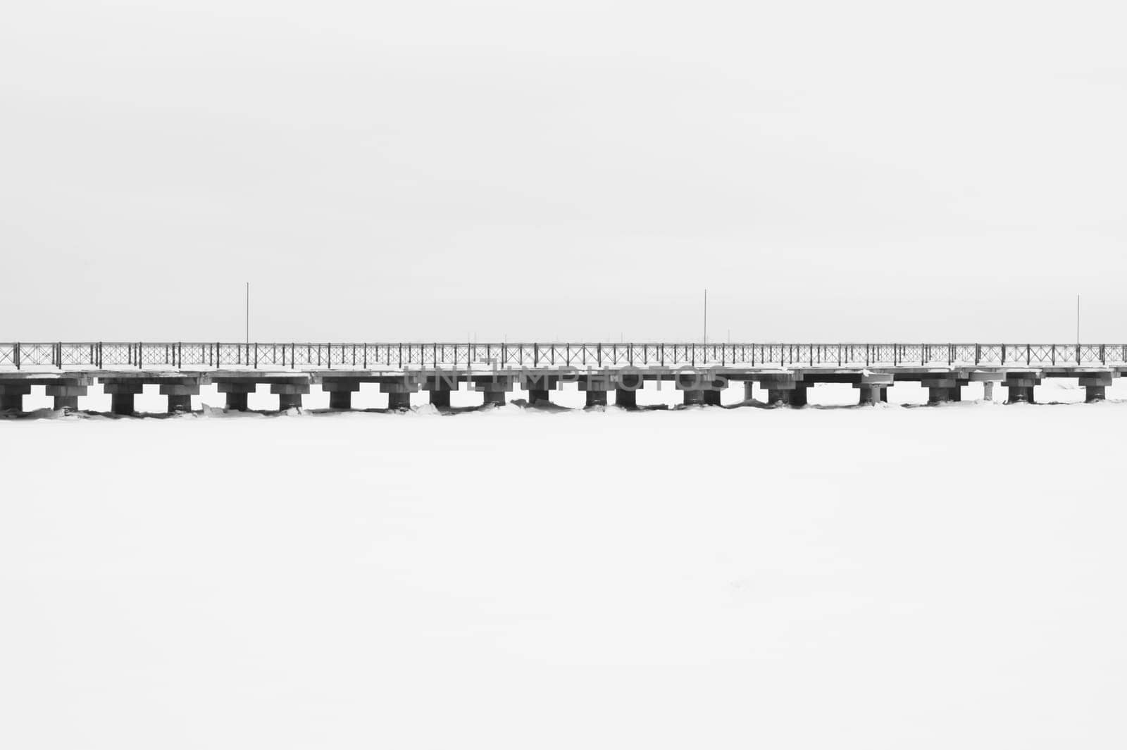 Bridge on the frozen lake. long footbridge dividing the horizon. conceptual minimalistic image. black and white background with copy space