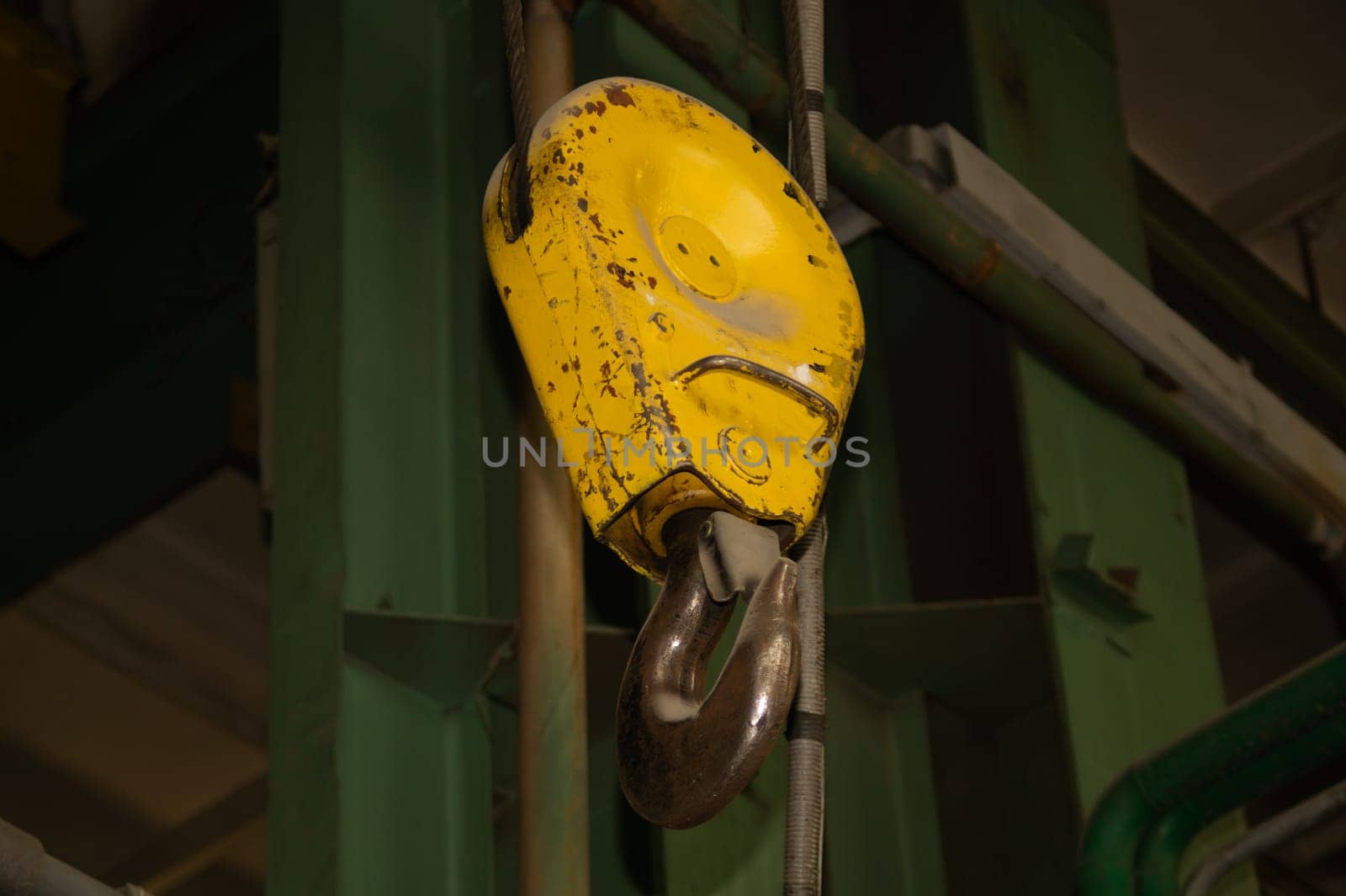 Yellow crane hook hanging in the factory. industrial background