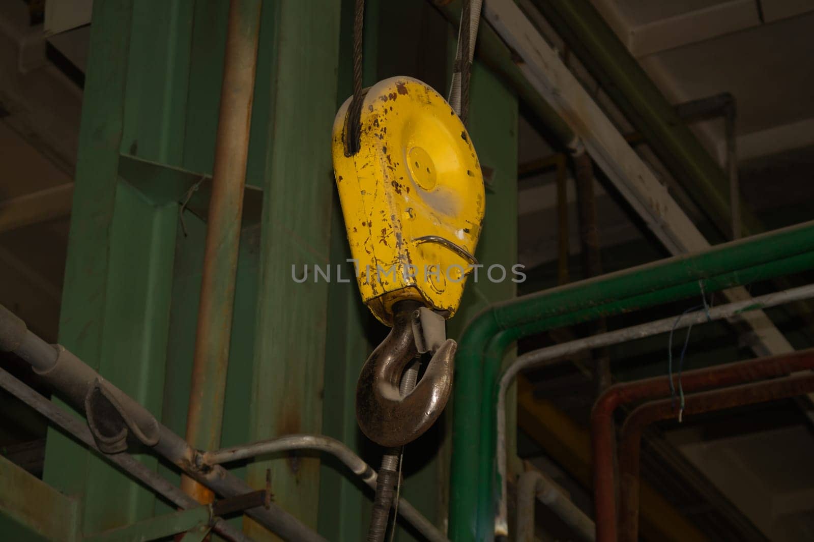 Yellow crane hook hanging in the factory. industrial background