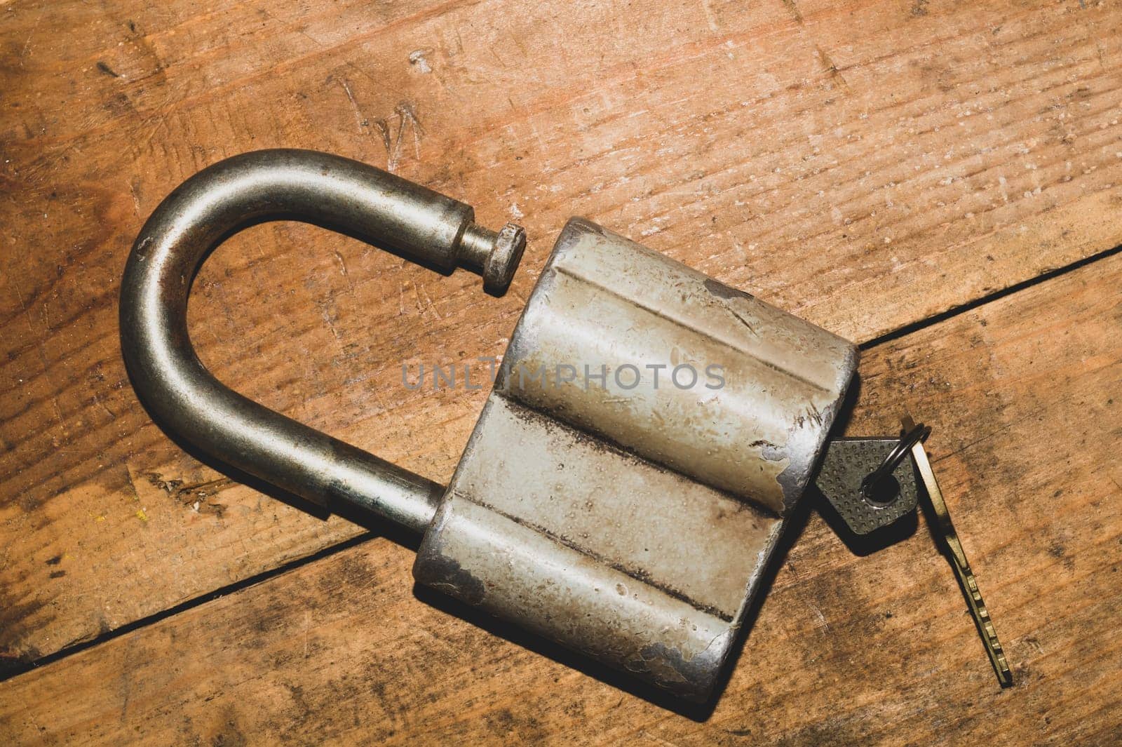 Old rusty lock with a key on a wooden table. Vintage padlock and key on wood background