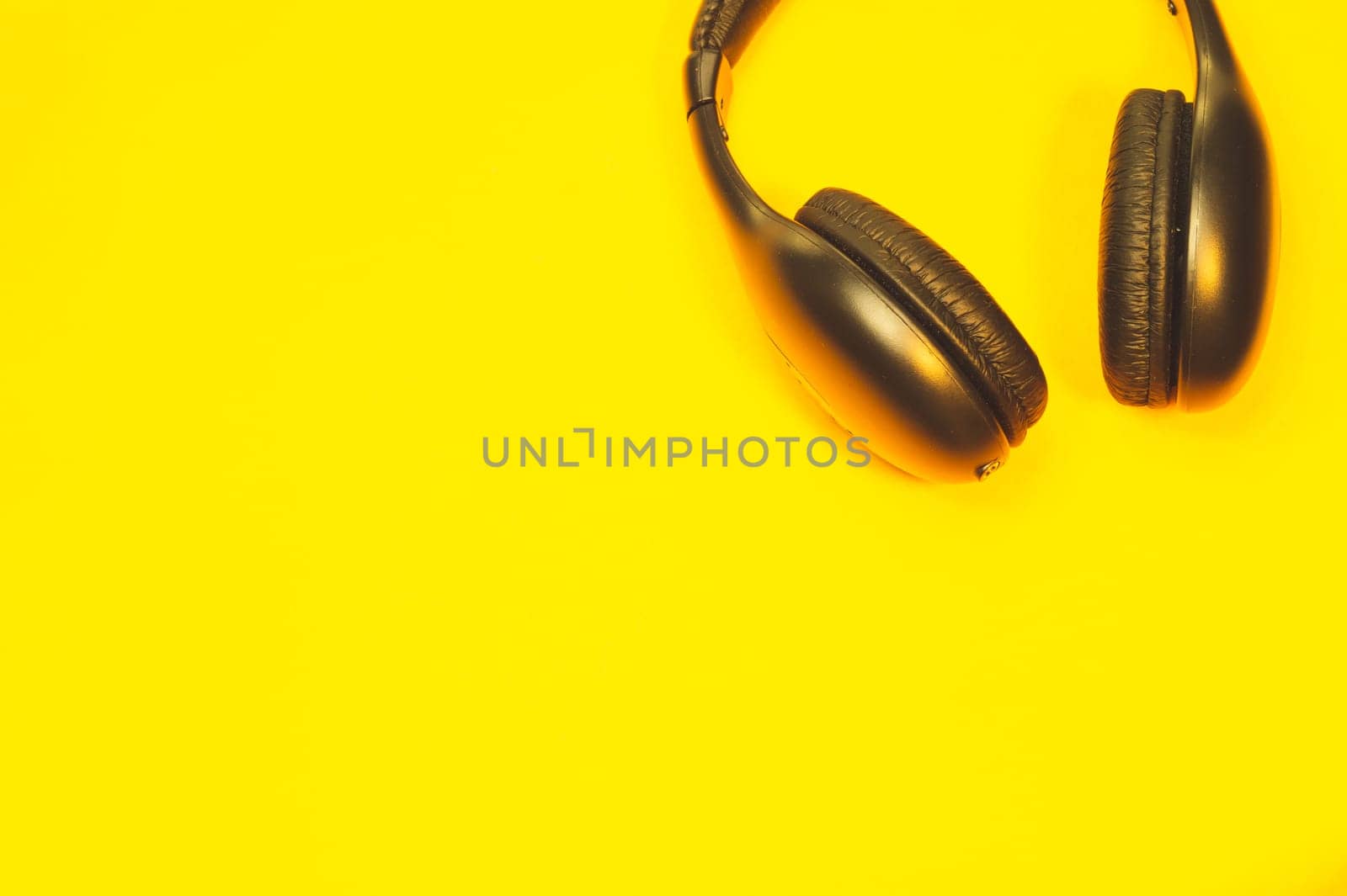 Black headphones on a yellow background. wireless earphones