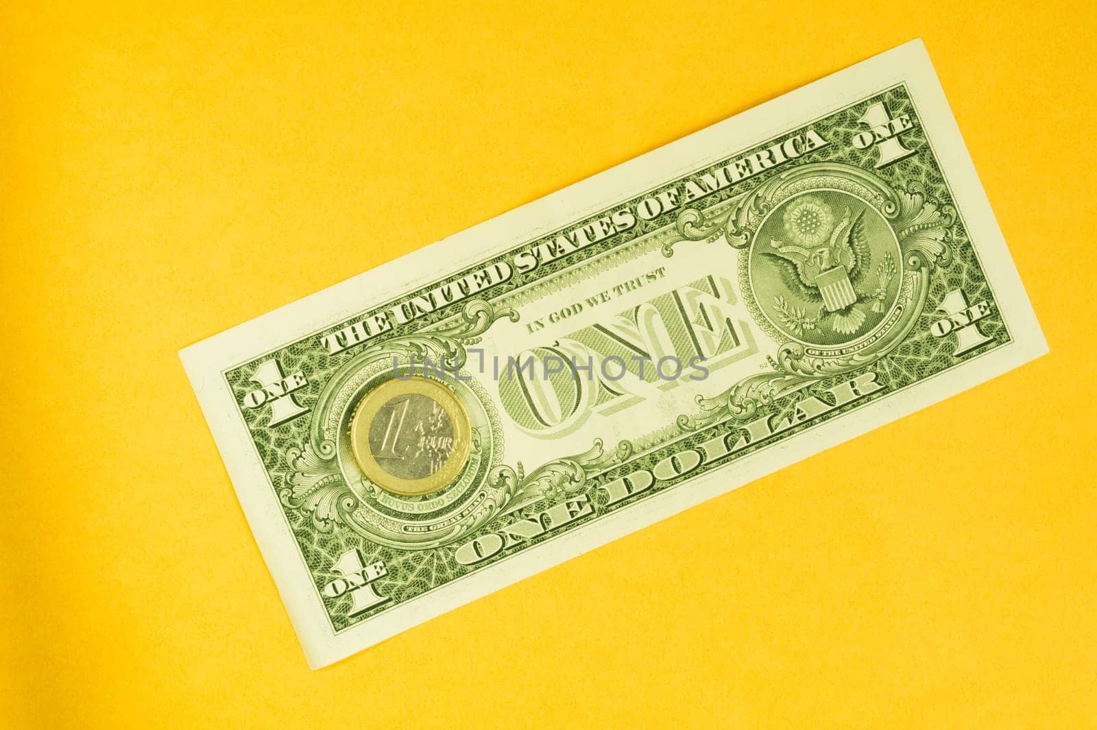 One dollar bill and one euro coin isolated on yellow background. coin lies on a banknote