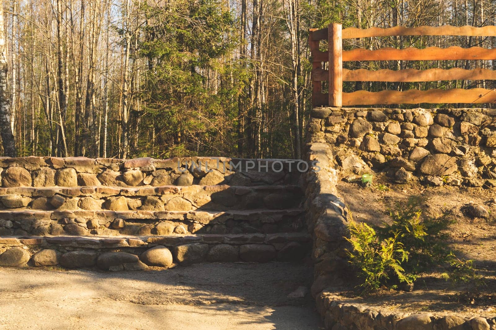 Natural stone ladder in the park. wooden fencing. nature background