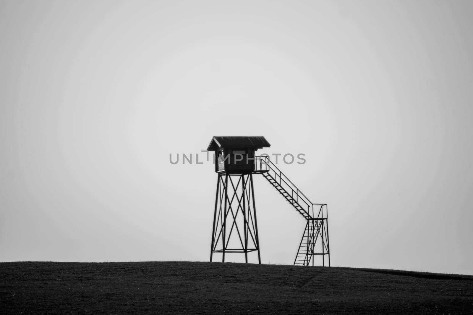 Lonely watch tower. observation post standing alone on the hill. hunting lodge in the field. solitude concept. shelter in the meadow