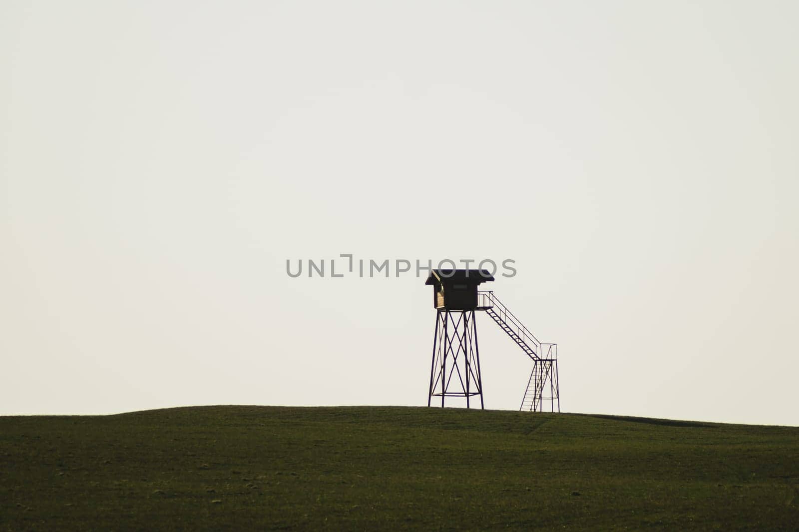 Lonely watch tower. observation post standing alone on the hill. hunting lodge in the field. solitude concept. shelter in the meadow