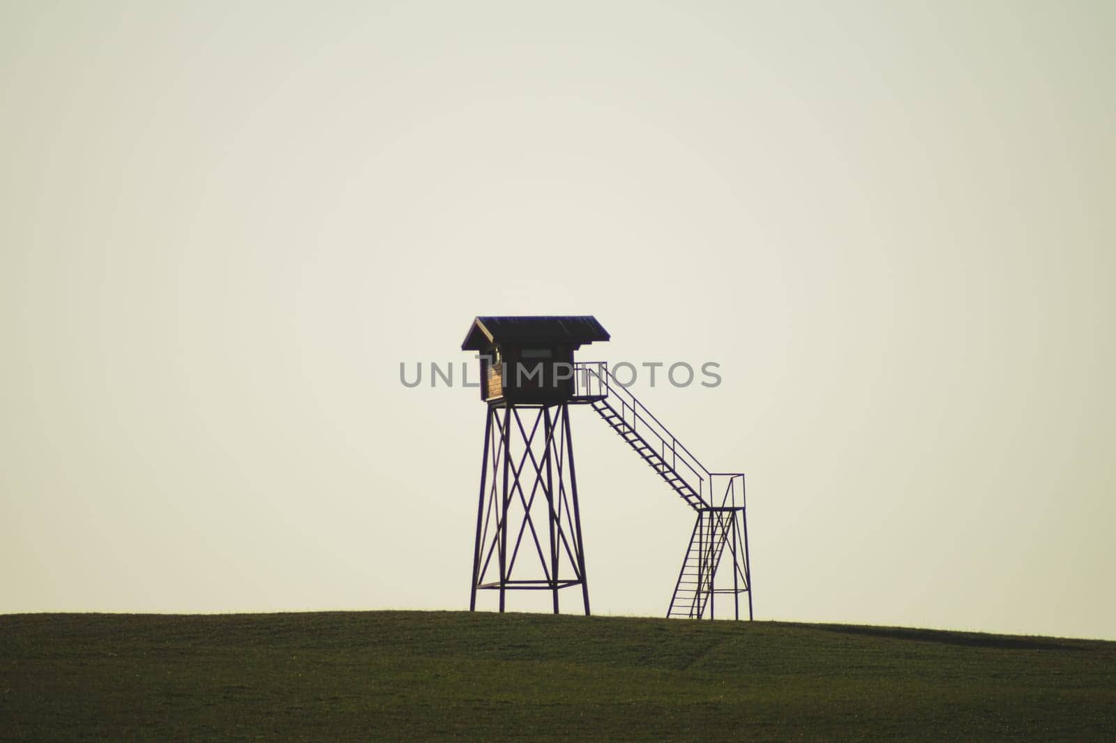 Lonely watch tower. observation post standing alone on the hill. hunting lodge in the field. solitude concept. shelter in the meadow