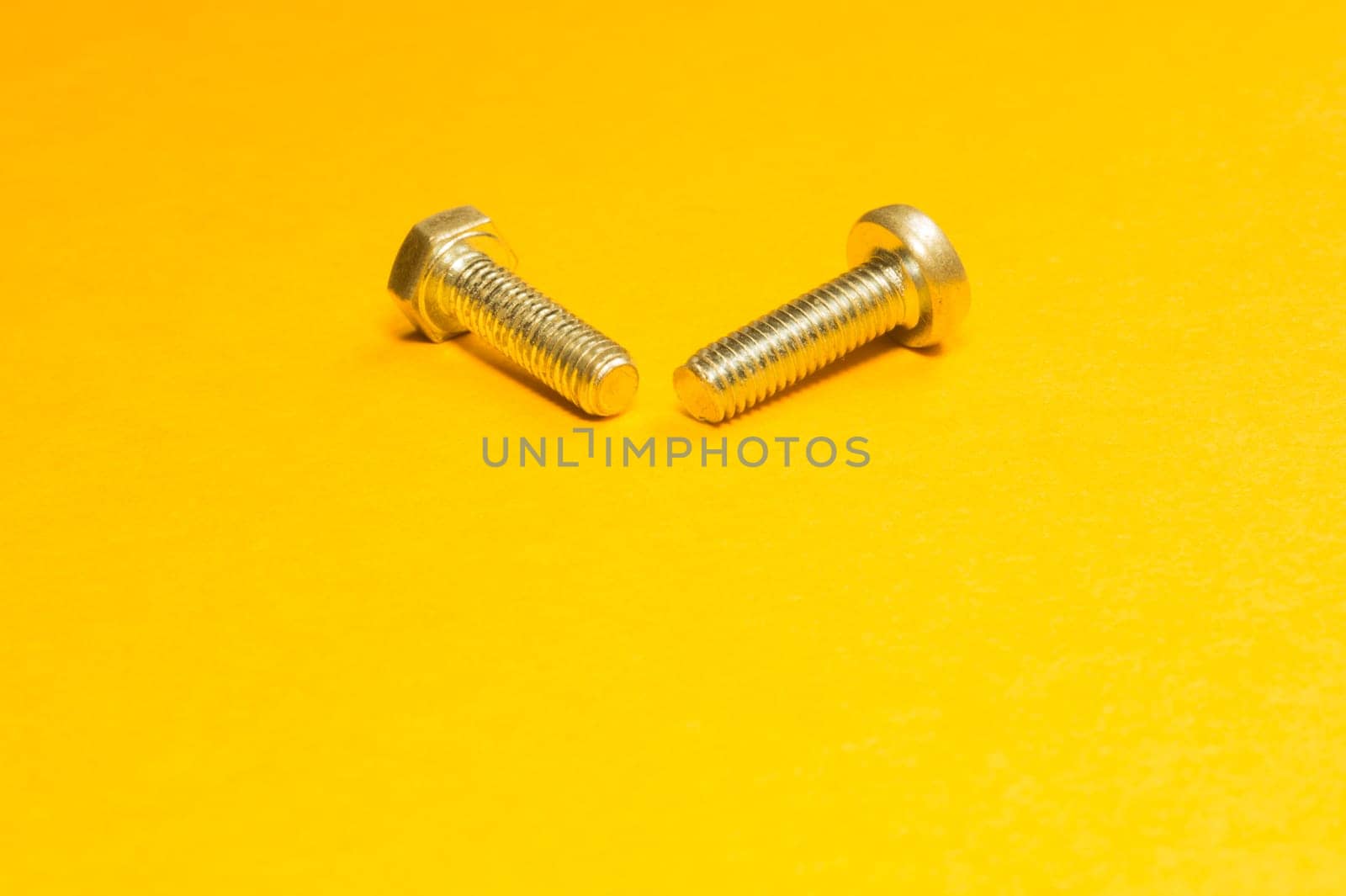 Steel screw on a yellow background. working tools
