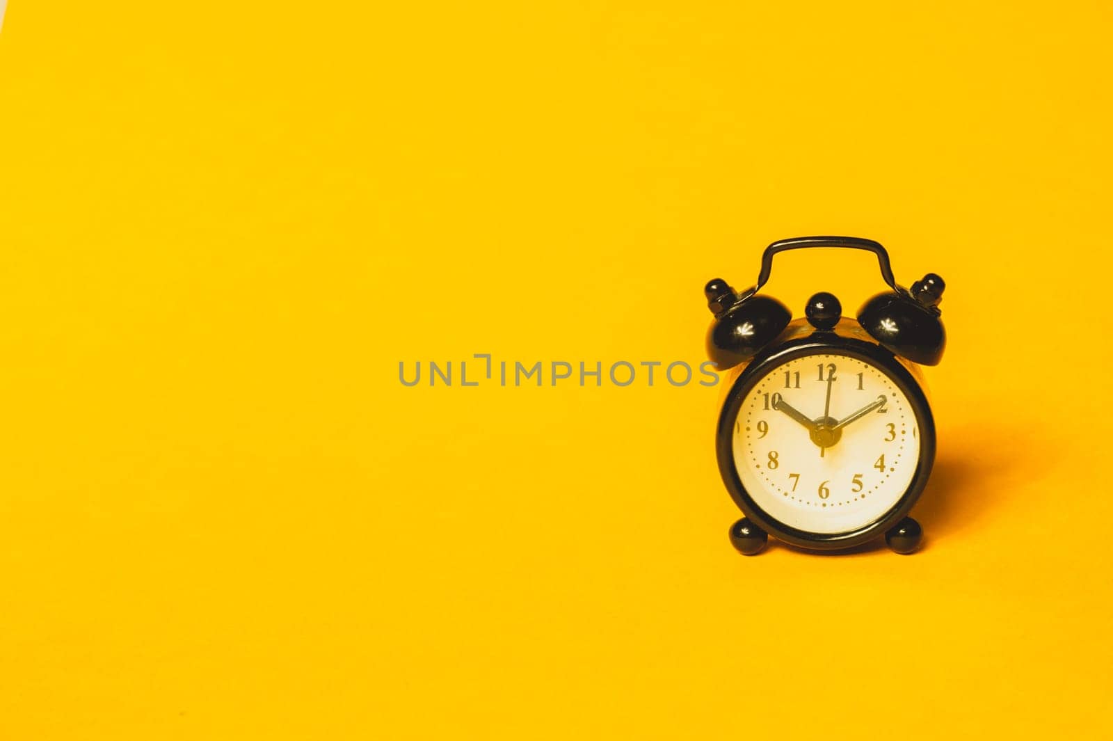 Classic alarm clock on yellow background. vintage watch with round dial. copy space