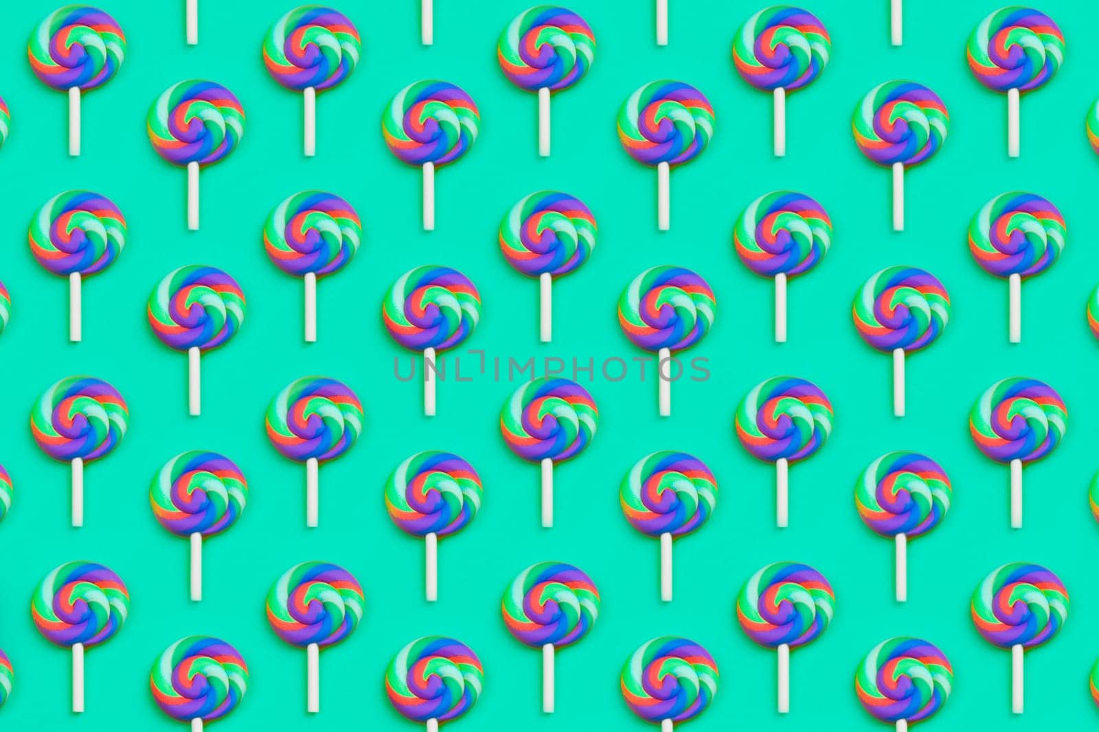 Lollipops are in a row. spiral candy pattern. lots of sweets on a turquoise background. festive decoration with candies