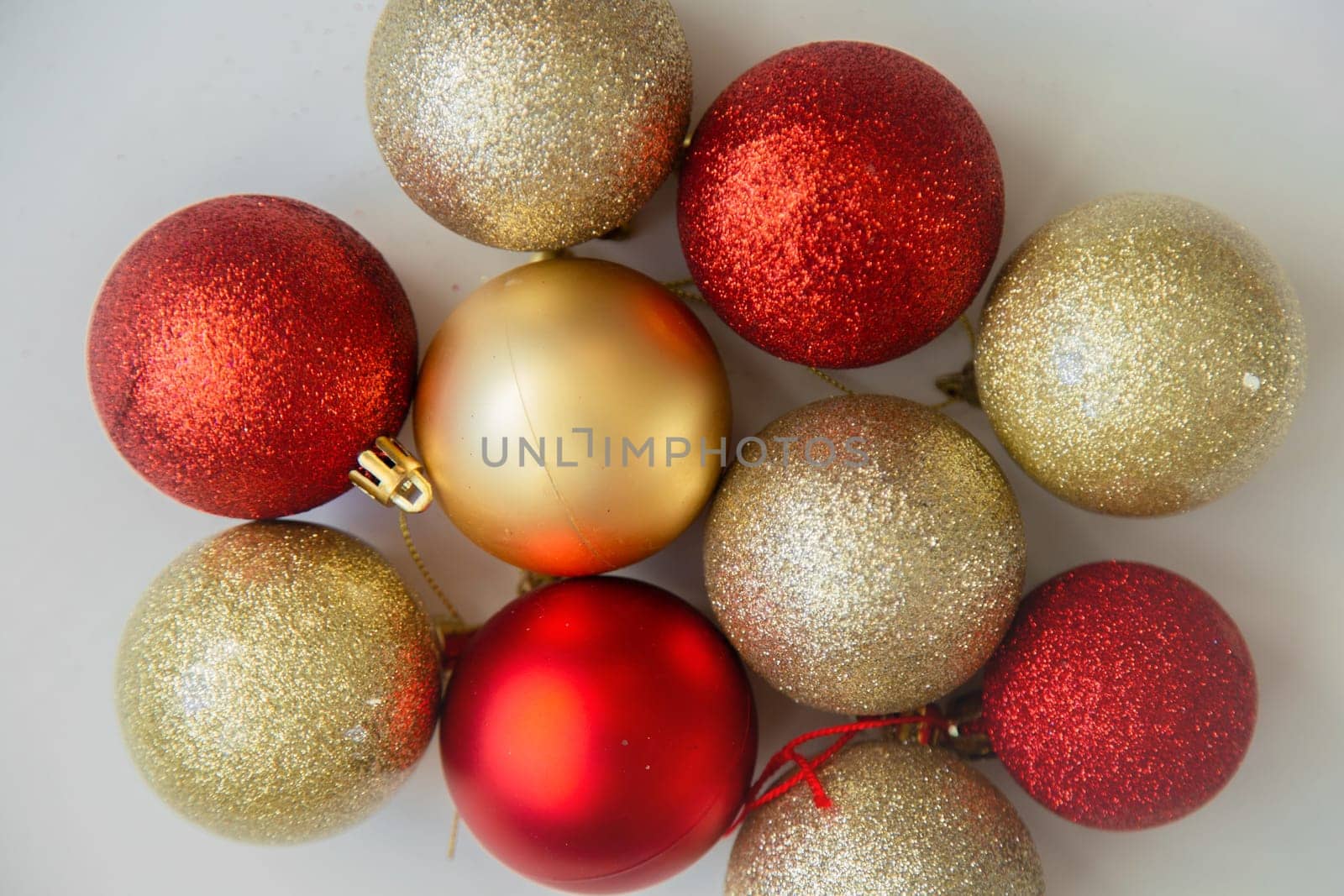 Golden and red Christmas balls with and without sequins lie on a white background. High quality photo