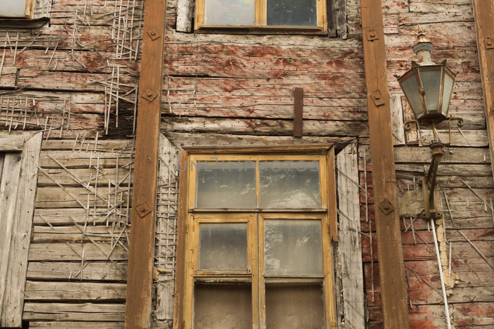 Windows of the old wooden house. wooden plank wall with windows and vintage lamp