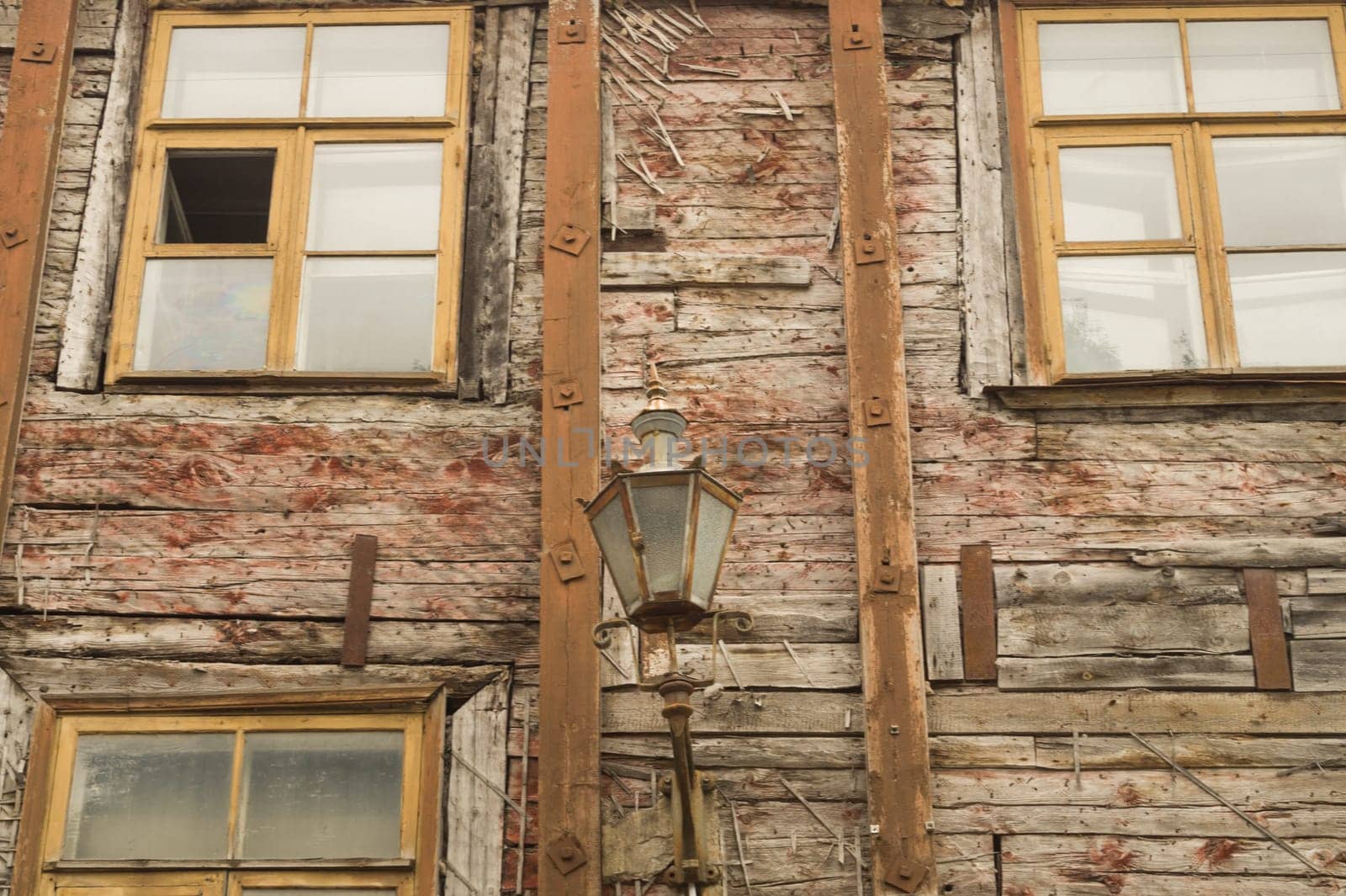 Windows of the old wooden house. wooden plank wall with windows and vintage lamp
