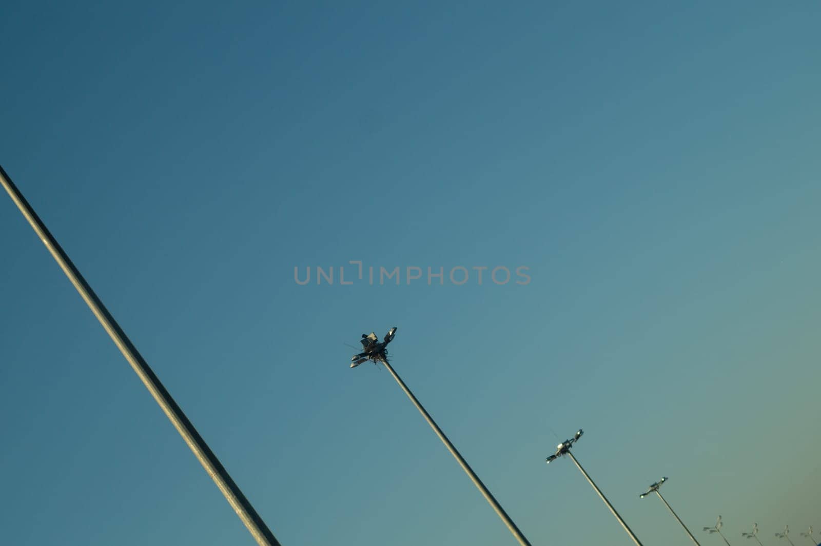 Street lamp posts standing in order on a highway with clear sky background