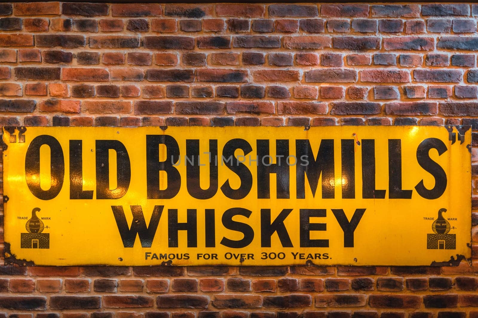 Bushmills, Northern Ireland, Aug 2019 Old Bushmills Whiskey famous for over 300 years sign on rustic brick wall in distillery visitor centre and shop