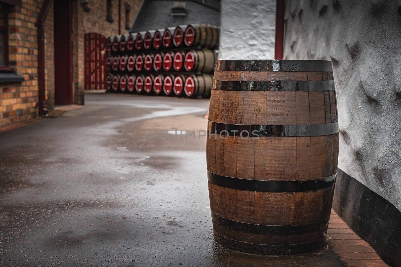 Old, vintage wooden whiskey barrel in an alley with rows of barrels in background, Bushmills town, Antrim, Northern Ireland