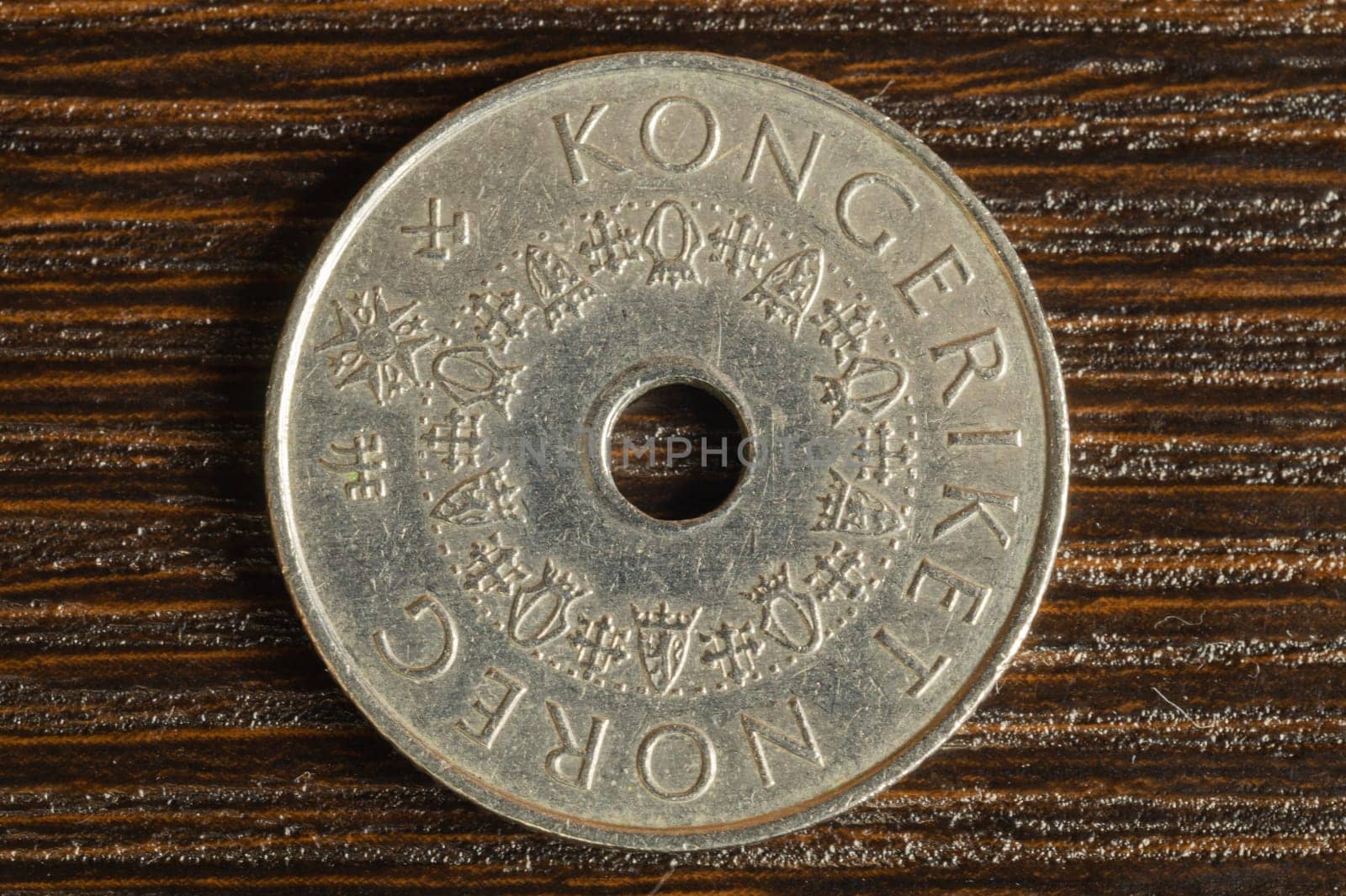 Norwegian coin on a dark wooden background. krone from Norway close up. coin with a hole