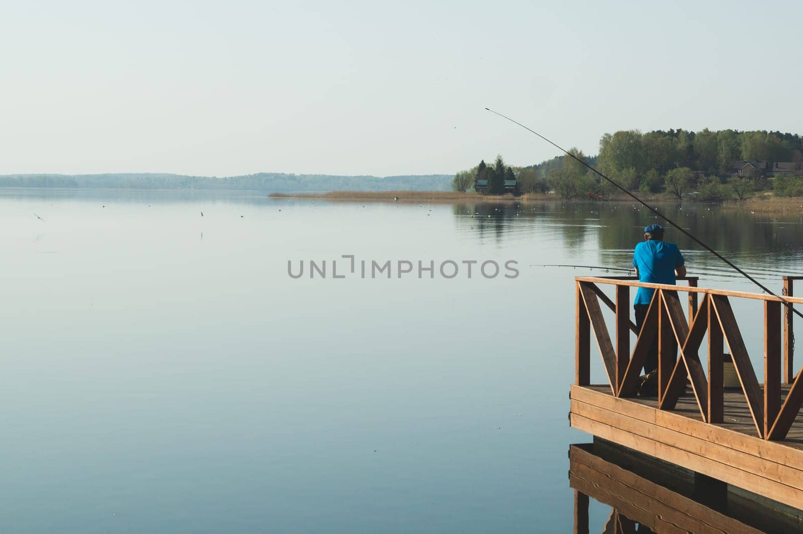Fisherman fishing on a pier. fisher on the shore. calm background