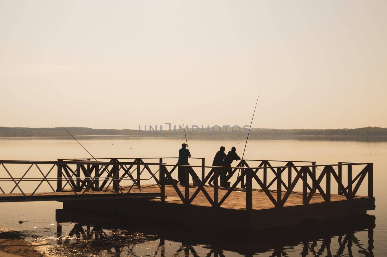 Fishermen catching fish on a pier. silhouette of fishers. calm background